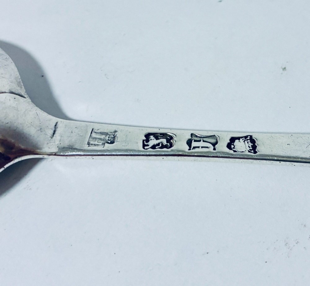 An 18th-century sterling silver serving spoon with a wide oval bowl and a smooth stem handle resting on a plain background. View VII