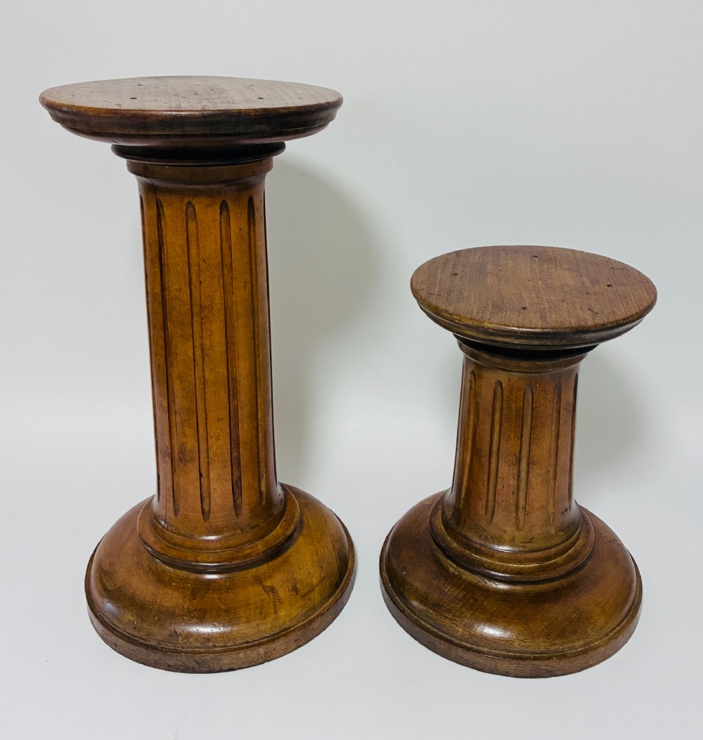 A pair of turned oak Neoclassical display pedestals featuring fluted columns and circular molded tops.