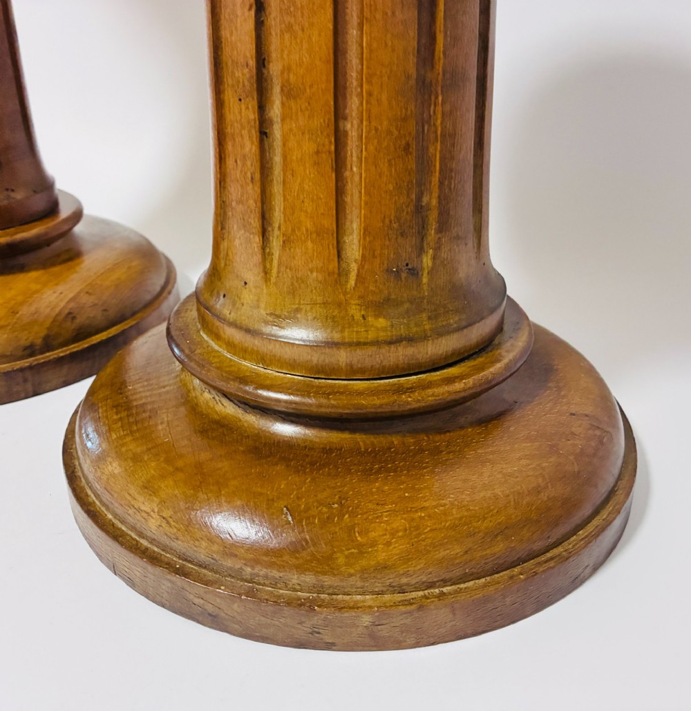 A pair of turned oak Neoclassical display pedestals featuring fluted columns and circular molded tops. View V