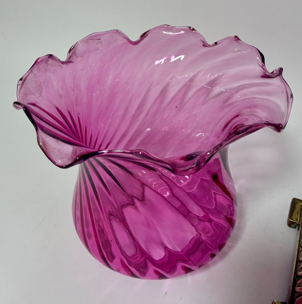A Victorian oil lamp featuring a swirl optique cranberry glass shade and reservoir set atop a brass column and relief-moulded square base. View IV