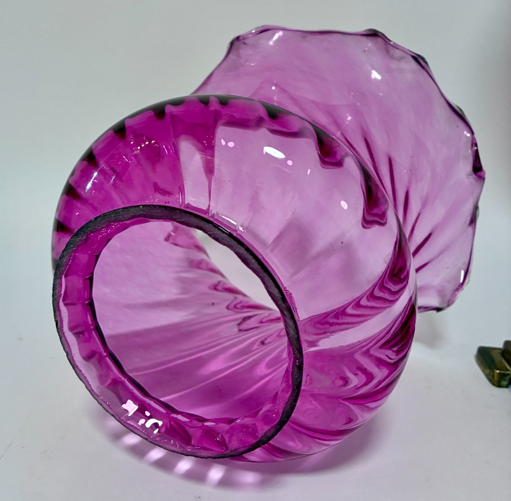 A Victorian oil lamp featuring a swirl optique cranberry glass shade and reservoir set atop a brass column and relief-moulded square base. View VI