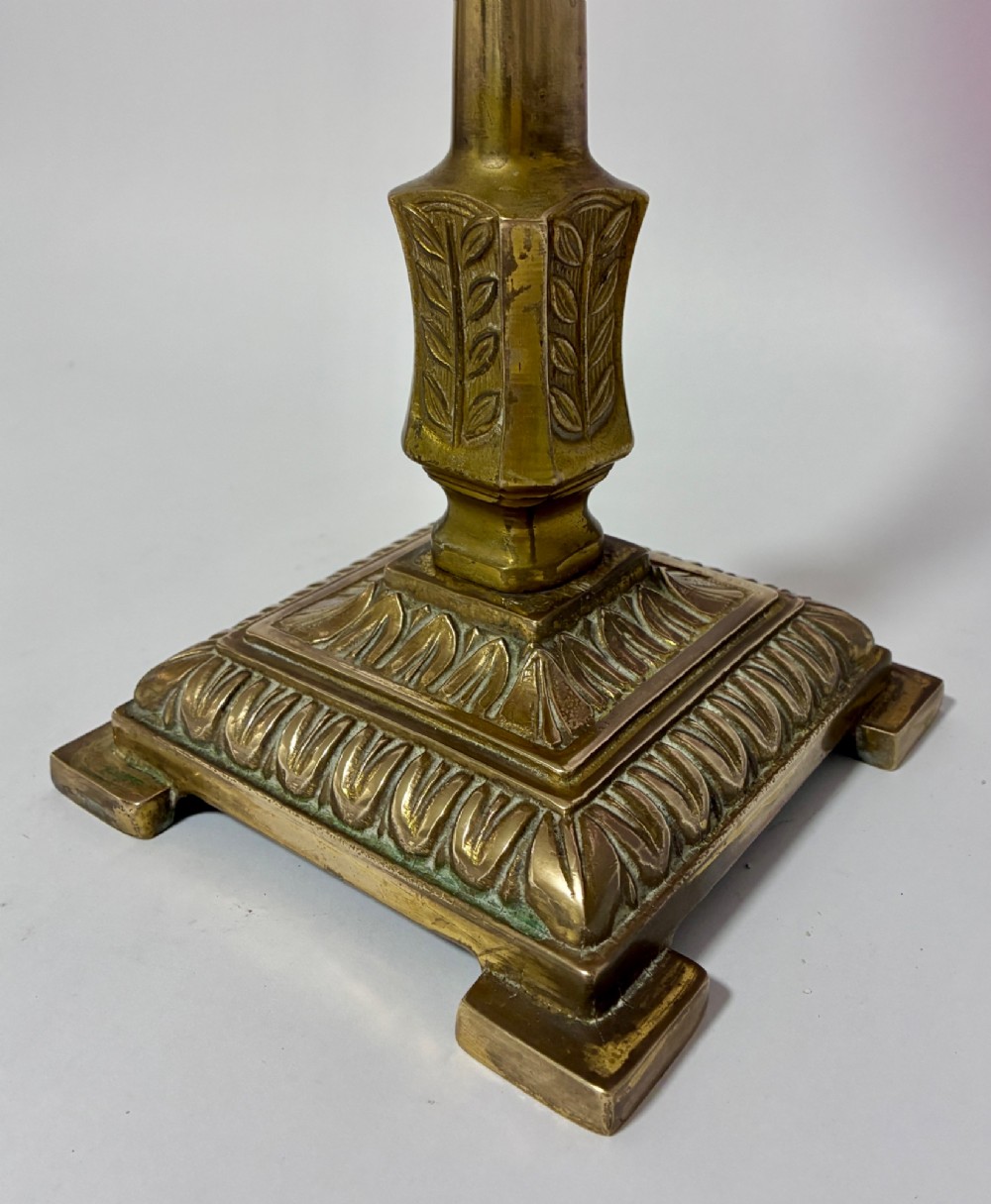 A Victorian oil lamp featuring a swirl optique cranberry glass shade and reservoir set atop a brass column and relief-moulded square base. View IX