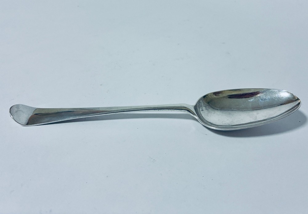 An 18th-century solid silver serving spoon featuring a plain tapered handle and an oval bowl.