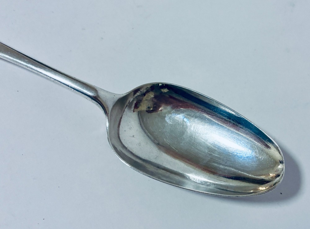 An 18th-century solid silver serving spoon featuring a plain tapered handle and an oval bowl. View III