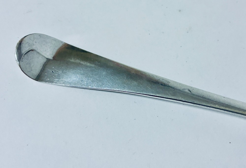 An 18th-century solid silver serving spoon featuring a plain tapered handle and an oval bowl. View IV
