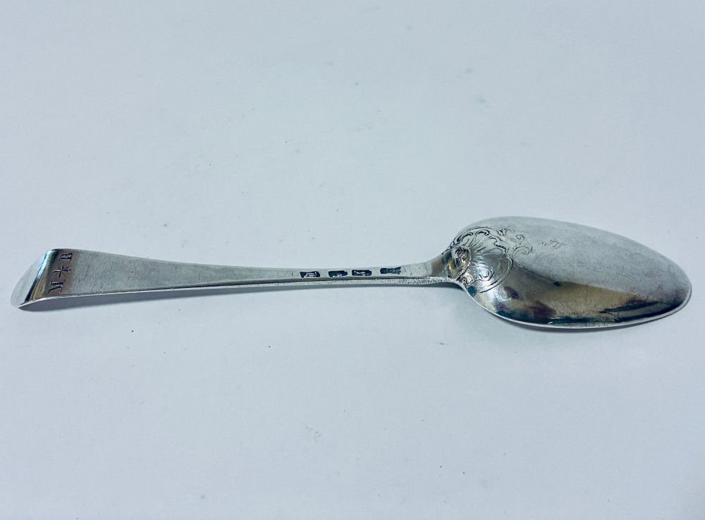An 18th-century solid silver serving spoon featuring a plain tapered handle and an oval bowl. View V