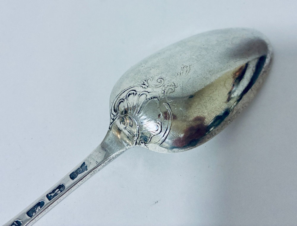 An 18th-century solid silver serving spoon featuring a plain tapered handle and an oval bowl. View VI