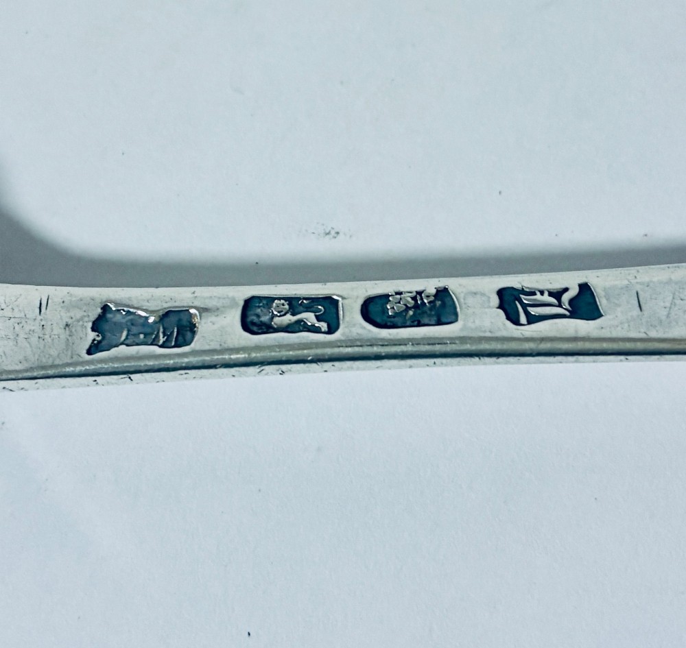 An 18th-century solid silver serving spoon featuring a plain tapered handle and an oval bowl. View IX