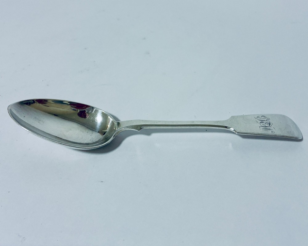 A sterling silver fiddle pattern tablespoon featuring an engraved monogram on the handle terminal and a polished oval bowl.
