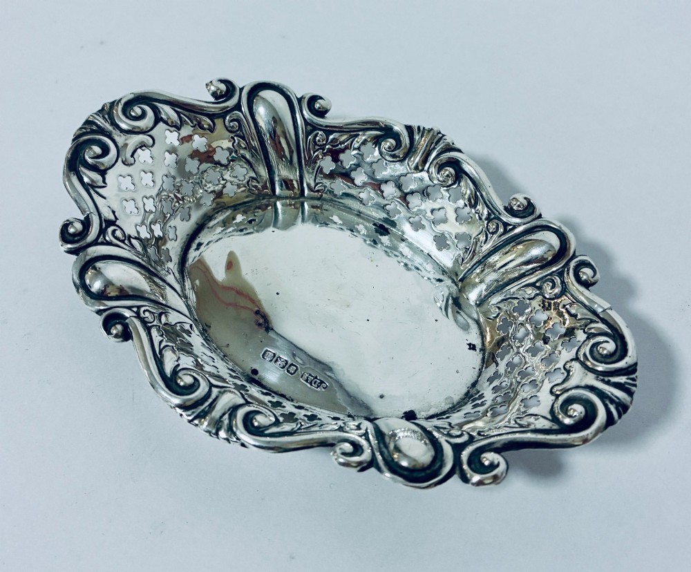 An oval antique silver bonbon dish featuring intricately pierced fretwork sides and a scrolled rim. View II