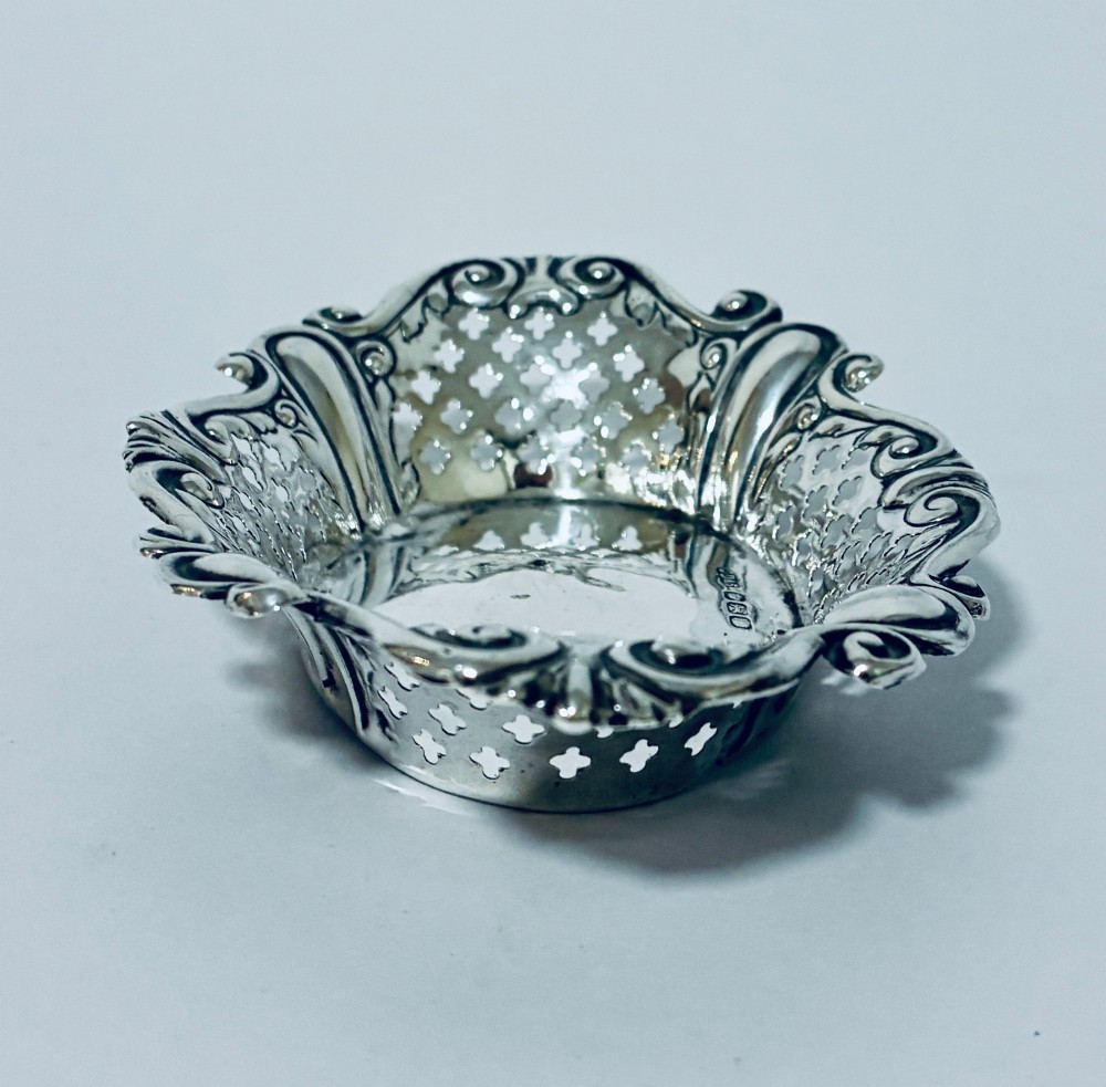 An oval antique silver bonbon dish featuring intricately pierced fretwork sides and a scrolled rim. View III