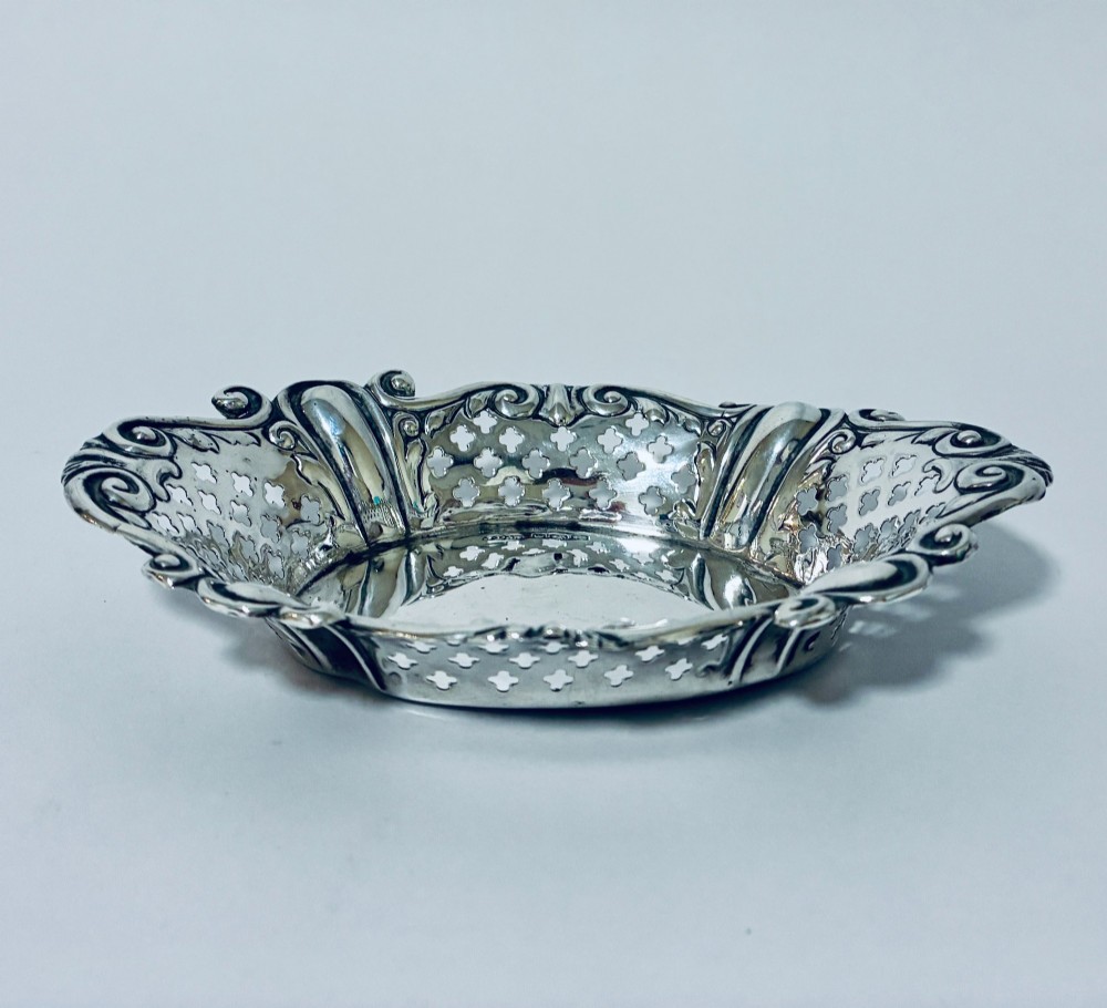 An oval antique silver bonbon dish featuring intricately pierced fretwork sides and a scrolled rim. View IV