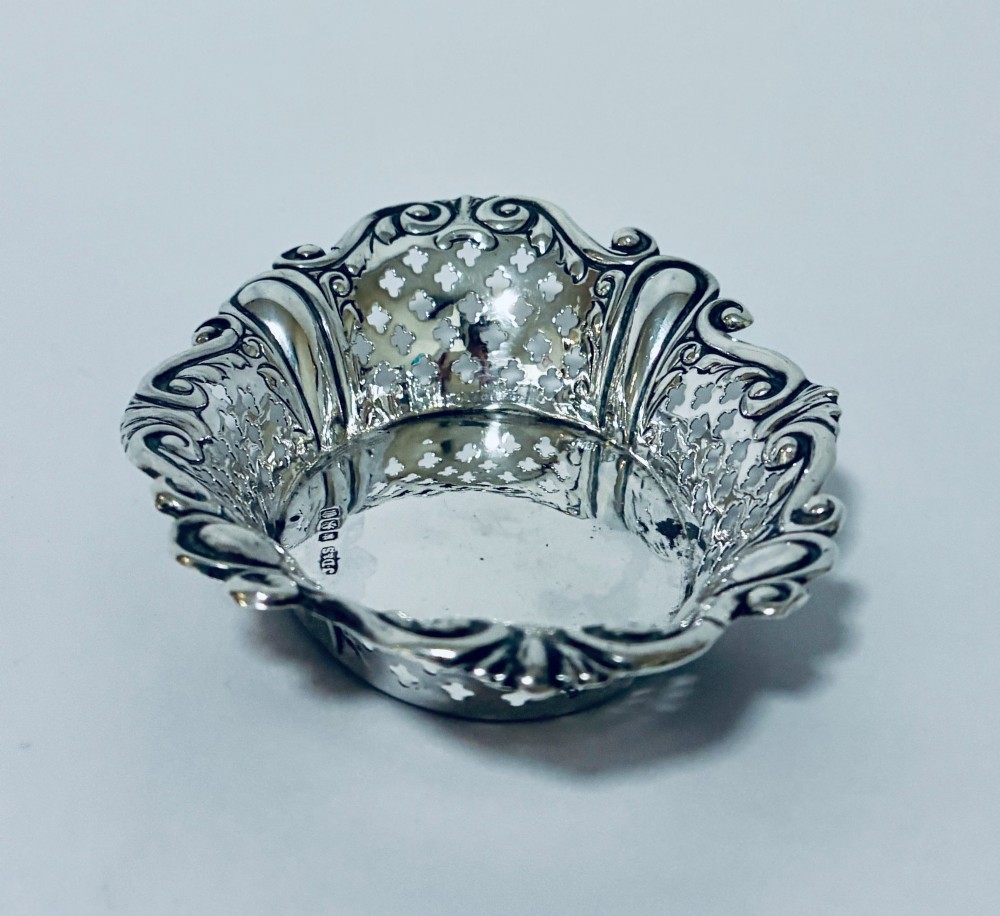 An oval antique silver bonbon dish featuring intricately pierced fretwork sides and a scrolled rim. View V