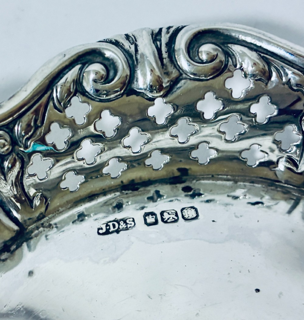 An oval antique silver bonbon dish featuring intricately pierced fretwork sides and a scrolled rim. View VI