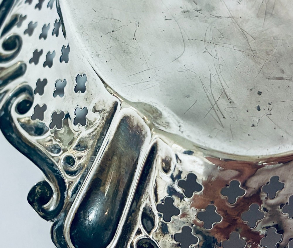 An oval antique silver bonbon dish featuring intricately pierced fretwork sides and a scrolled rim. View X