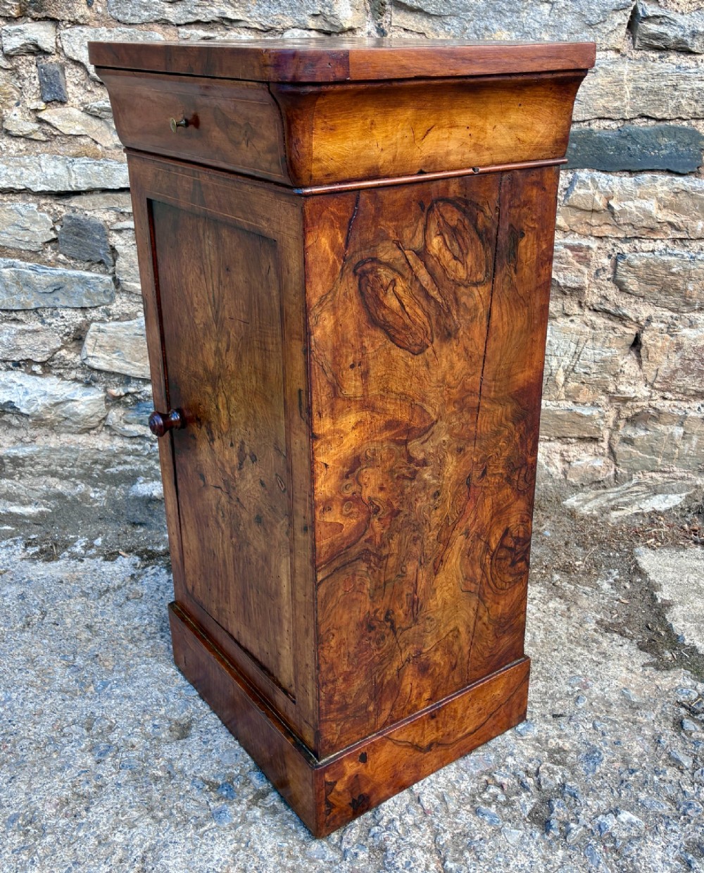 An antique French walnut pot cupboard with a figured burr walnut door panel, frieze drawer, and plinth base. View III