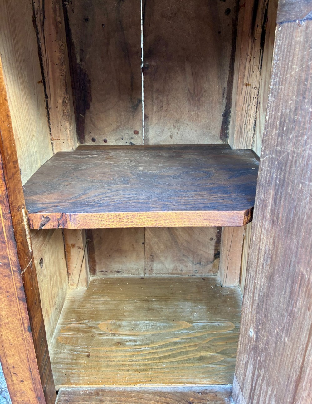 An antique French walnut pot cupboard with a figured burr walnut door panel, frieze drawer, and plinth base. View XIV