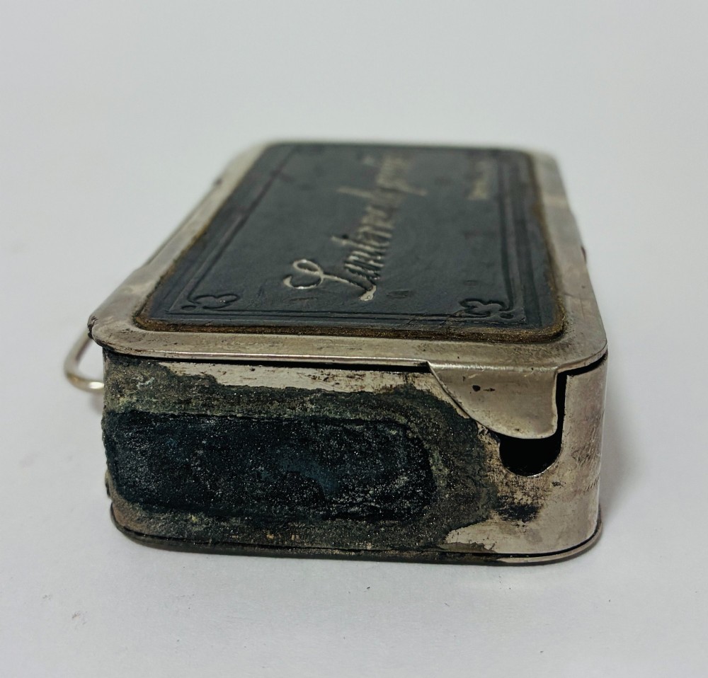 An open nickel-plated folding pocket lantern containing a small wax candle and a glass panel stamped with patent text. View X