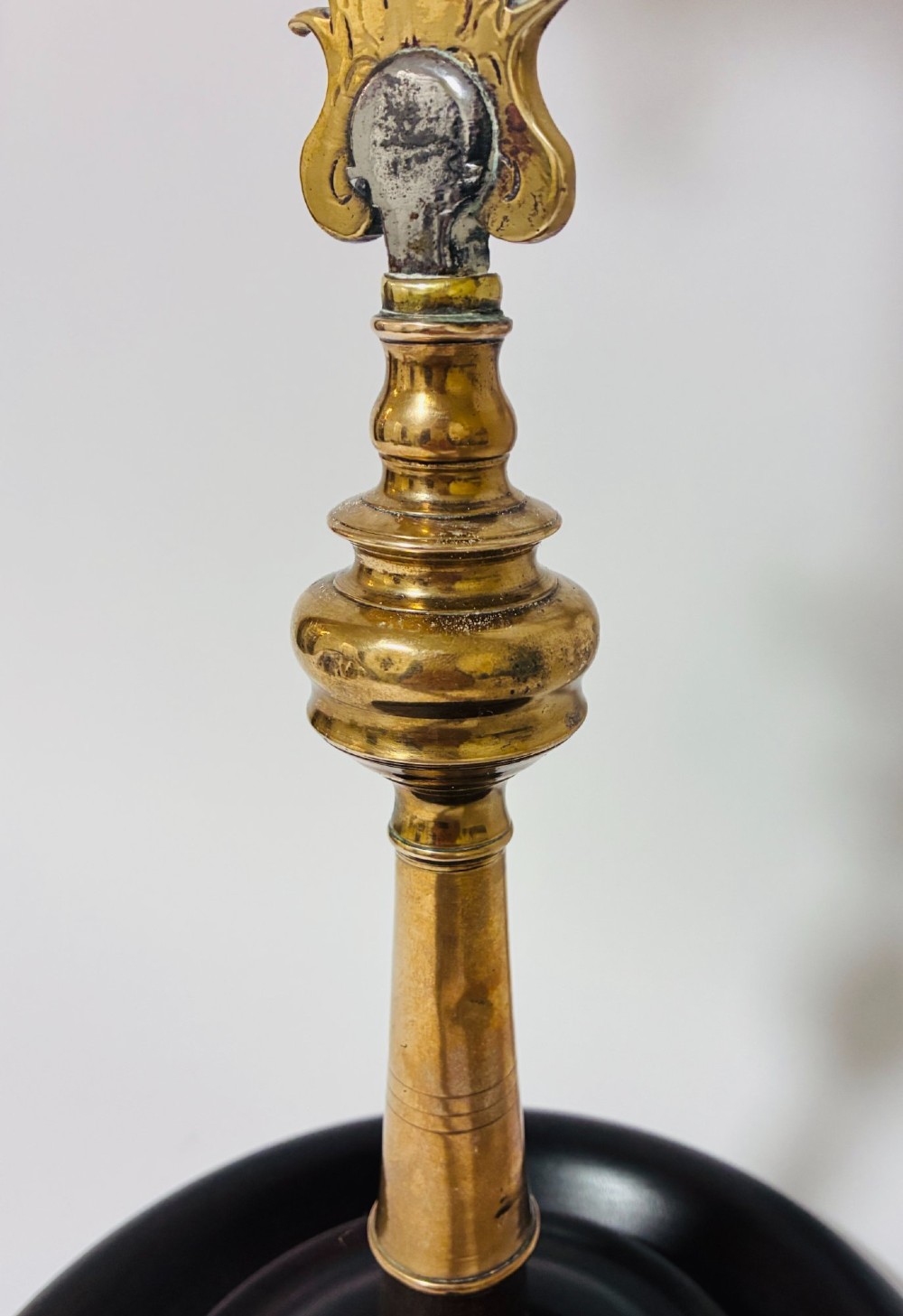 An antique brass processional cross featuring a detailed crucifix figure, fleur-de-lis terminal accents, and engraved motifs, mounted on a turned dark wood stand. View VIII