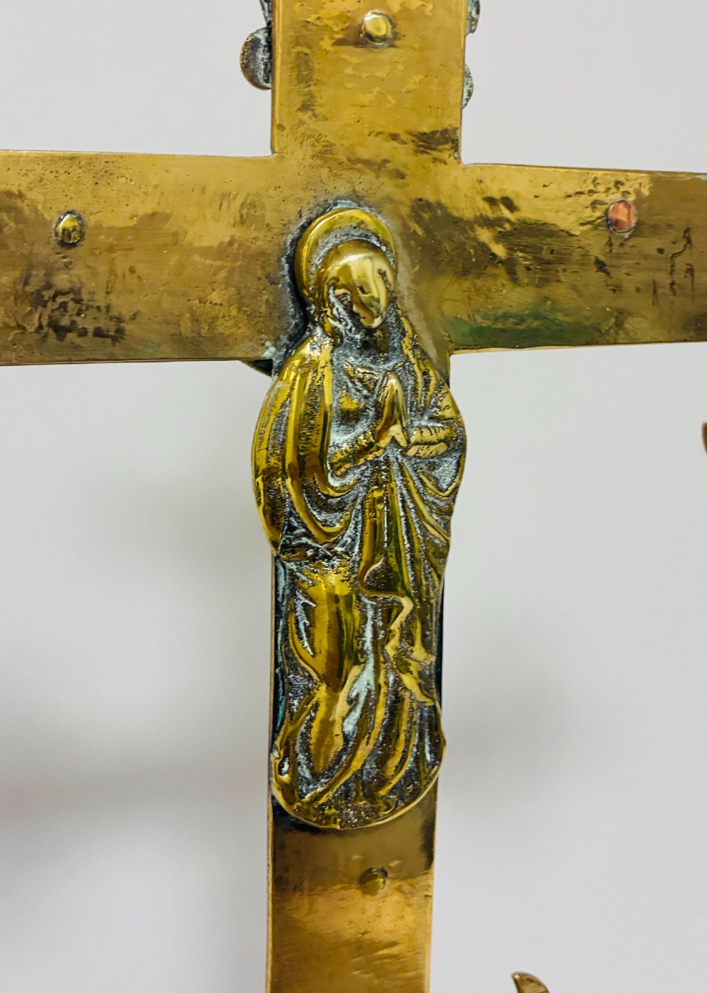 An antique brass processional cross featuring a detailed crucifix figure, fleur-de-lis terminal accents, and engraved motifs, mounted on a turned dark wood stand. View XIII