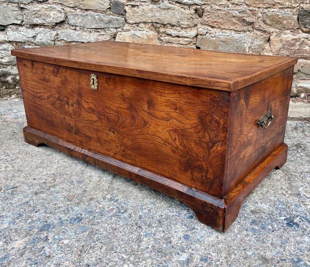 A low rectangular warm brown elm blanket box featuring a hinged top, polished finish, brass keyhole escutcheon, and bracket feet. View VIII