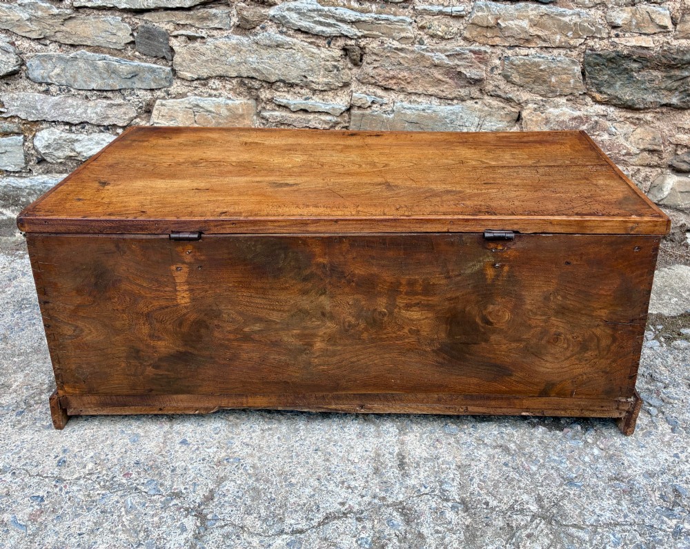 A low rectangular warm brown elm blanket box featuring a hinged top, polished finish, brass keyhole escutcheon, and bracket feet. View X