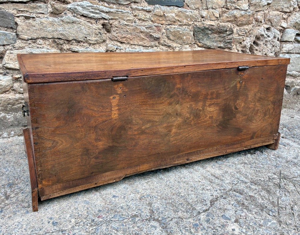 A low rectangular warm brown elm blanket box featuring a hinged top, polished finish, brass keyhole escutcheon, and bracket feet. View XI