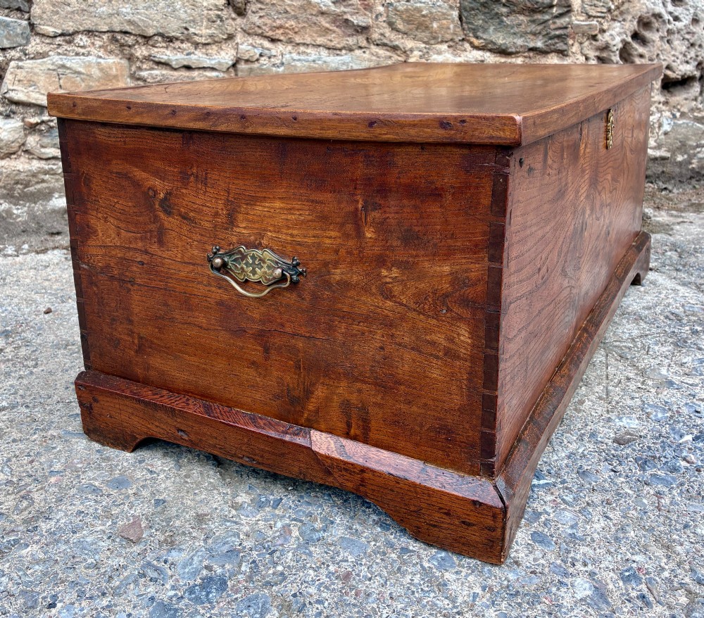A low rectangular warm brown elm blanket box featuring a hinged top, polished finish, brass keyhole escutcheon, and bracket feet. View XIII