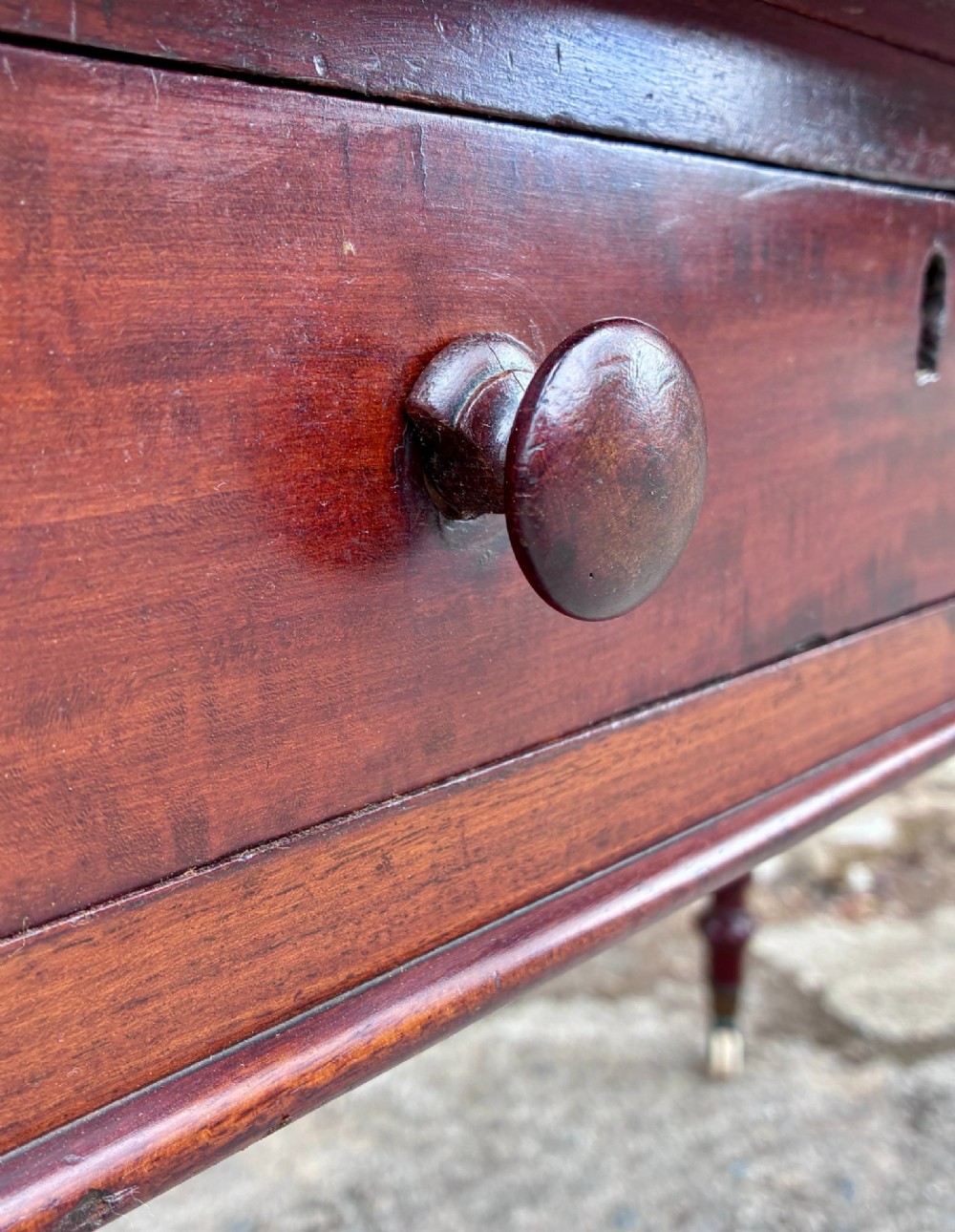 A Victorian mahogany writing table featuring a green gilt-tooled leather writing surface, two drawers with turned knob handles, and turned tapered legs resting on ceramic castors. View XIV