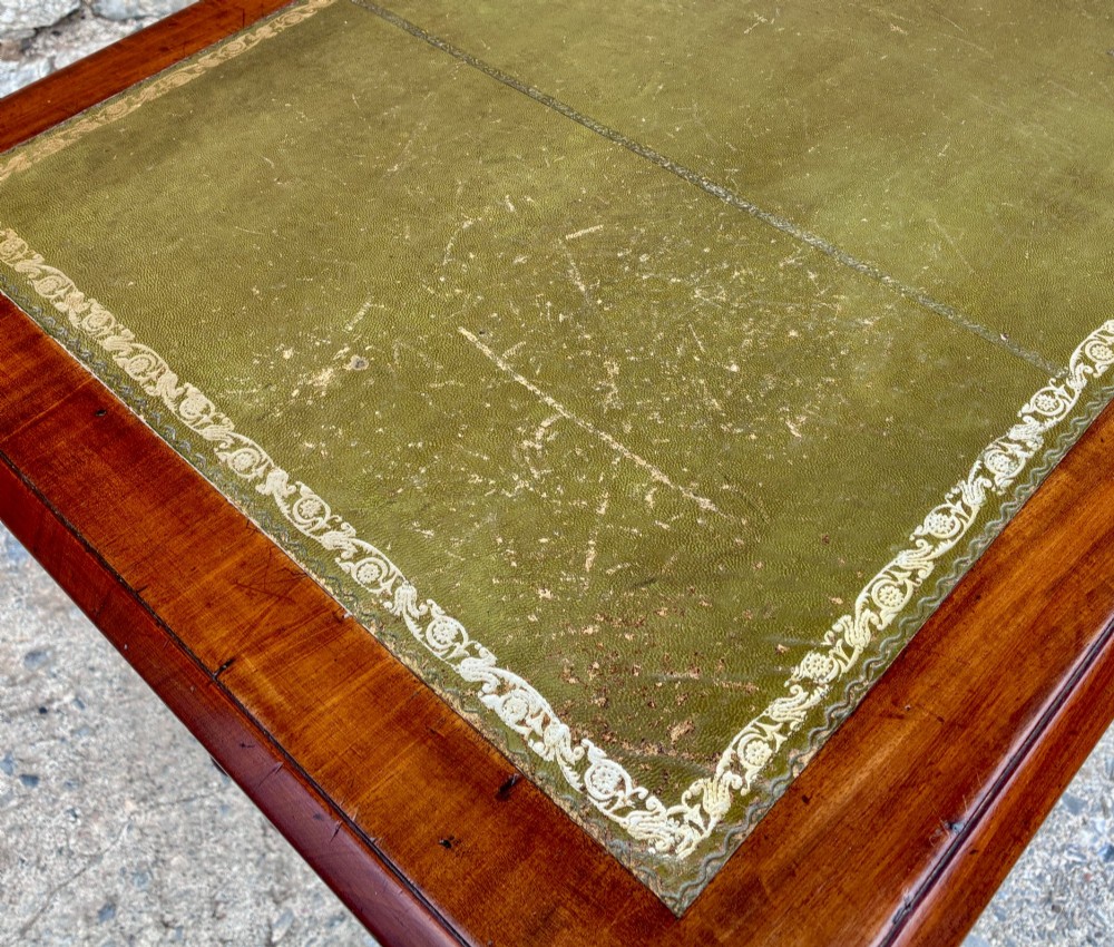 A Victorian mahogany writing table featuring a green gilt-tooled leather writing surface, two drawers with turned knob handles, and turned tapered legs resting on ceramic castors. View XV