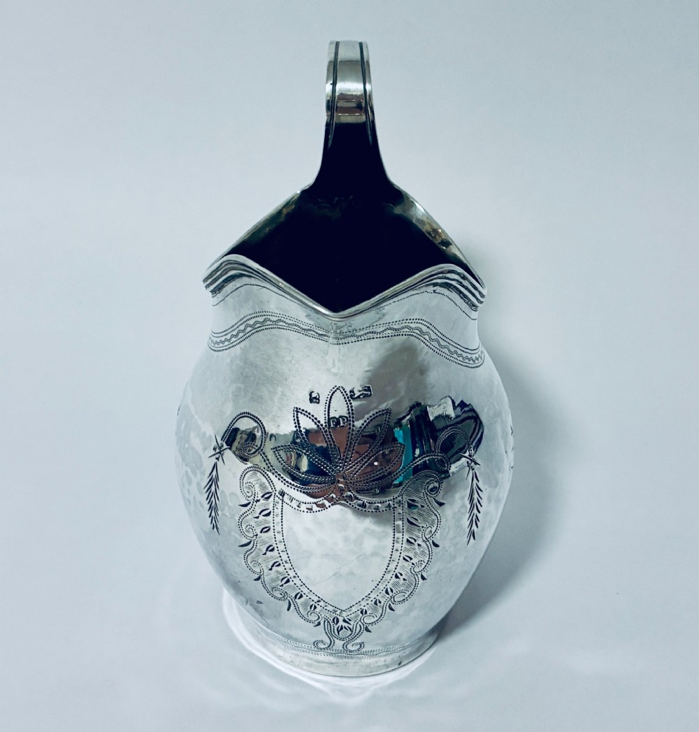 A Georgian sterling silver cream jug featuring a high loop handle, poured spout, and bright-cut star motif engraving on its body. View III