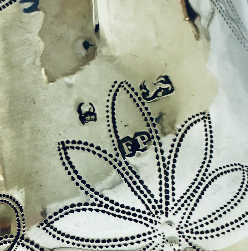 A Georgian sterling silver cream jug featuring a high loop handle, poured spout, and bright-cut star motif engraving on its body. View IX