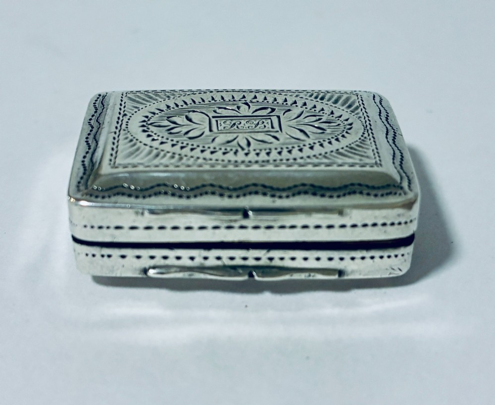 A small rectangular Georgian sterling silver vinaigrette box featuring bright-cut foliage engraving and a central monogrammed cartouche. View III