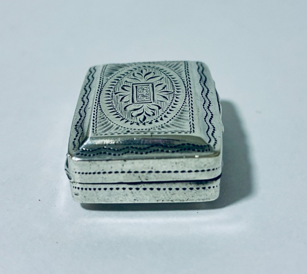 A small rectangular Georgian sterling silver vinaigrette box featuring bright-cut foliage engraving and a central monogrammed cartouche. View VI