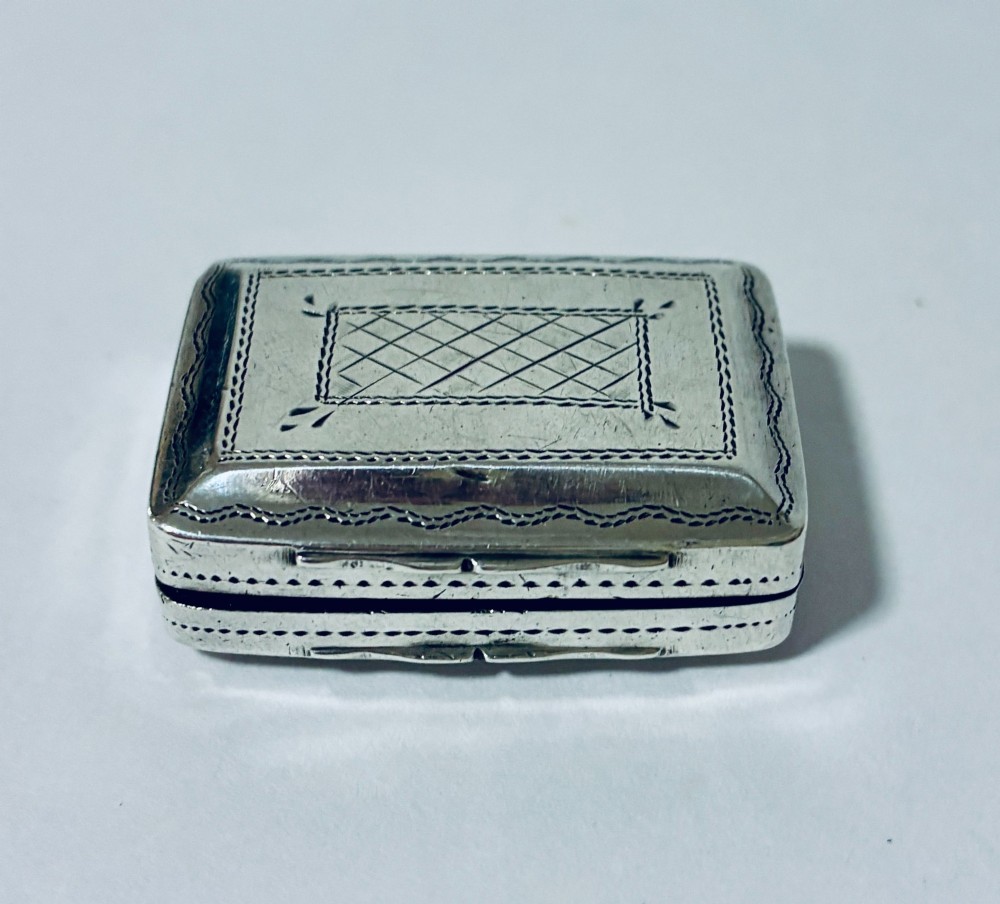 A small rectangular Georgian sterling silver vinaigrette box featuring bright-cut foliage engraving and a central monogrammed cartouche. View VIII