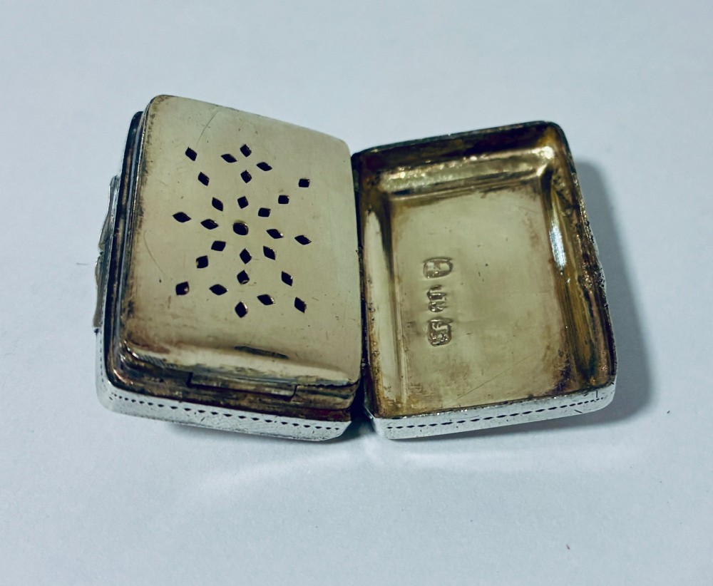 A small rectangular Georgian sterling silver vinaigrette box featuring bright-cut foliage engraving and a central monogrammed cartouche. View IX