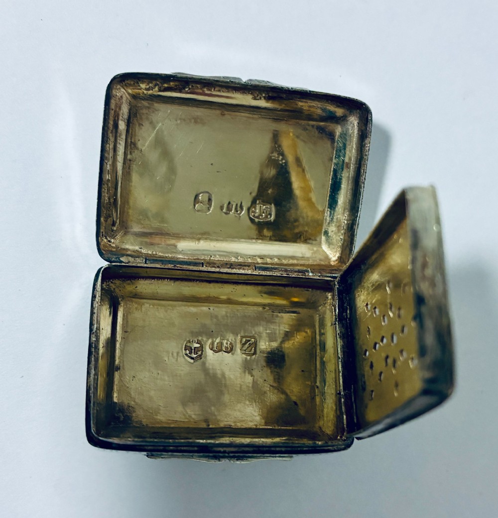 A small rectangular Georgian sterling silver vinaigrette box featuring bright-cut foliage engraving and a central monogrammed cartouche. View XI
