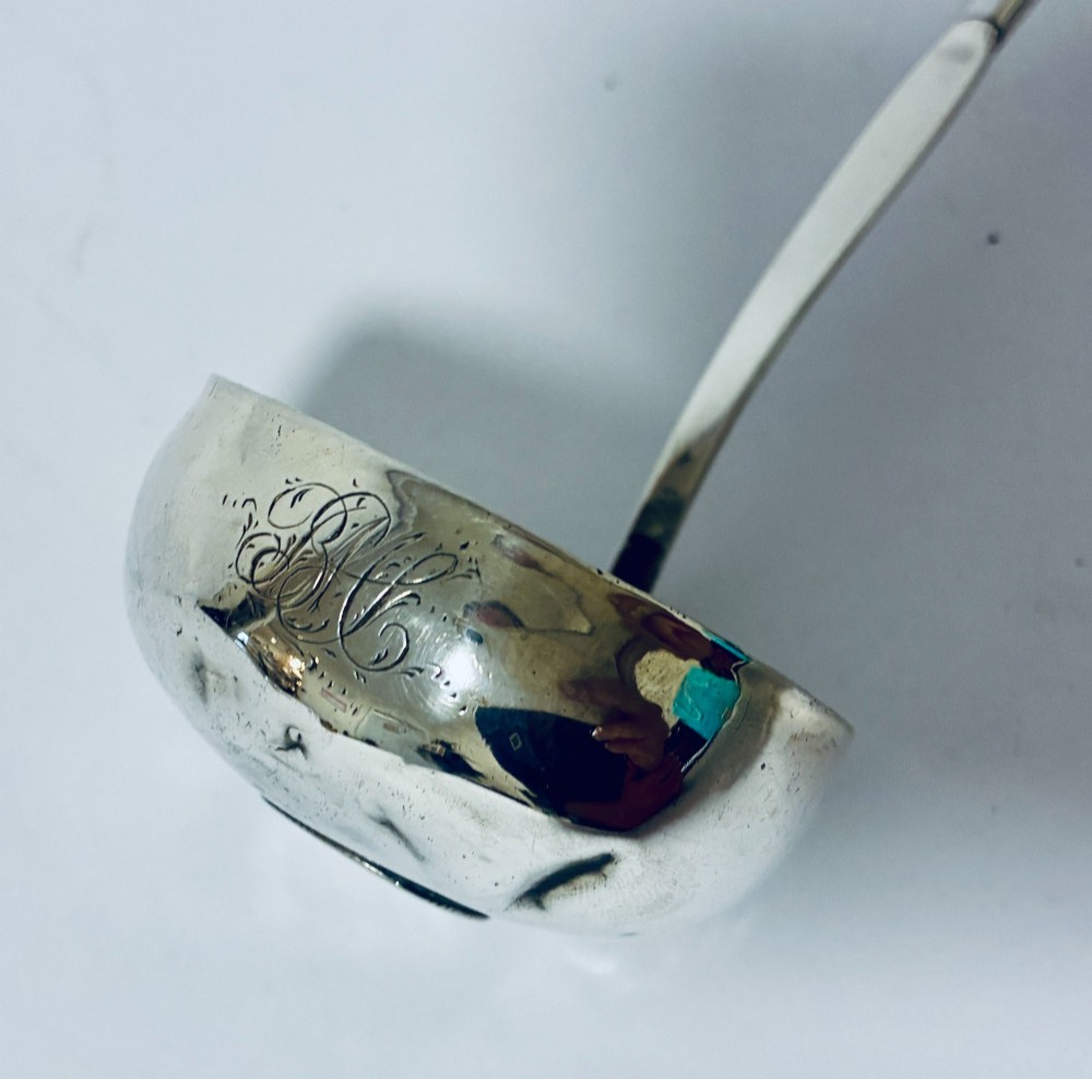 An antique Georgian silver toddy ladle featuring a deep circular silver bowl attached to a long, dark twisted handle. View III