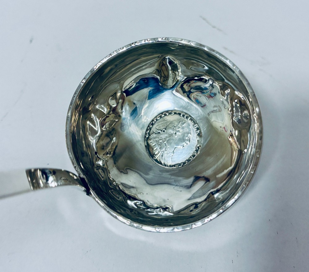 An antique Georgian silver toddy ladle featuring a deep circular silver bowl attached to a long, dark twisted handle. View V