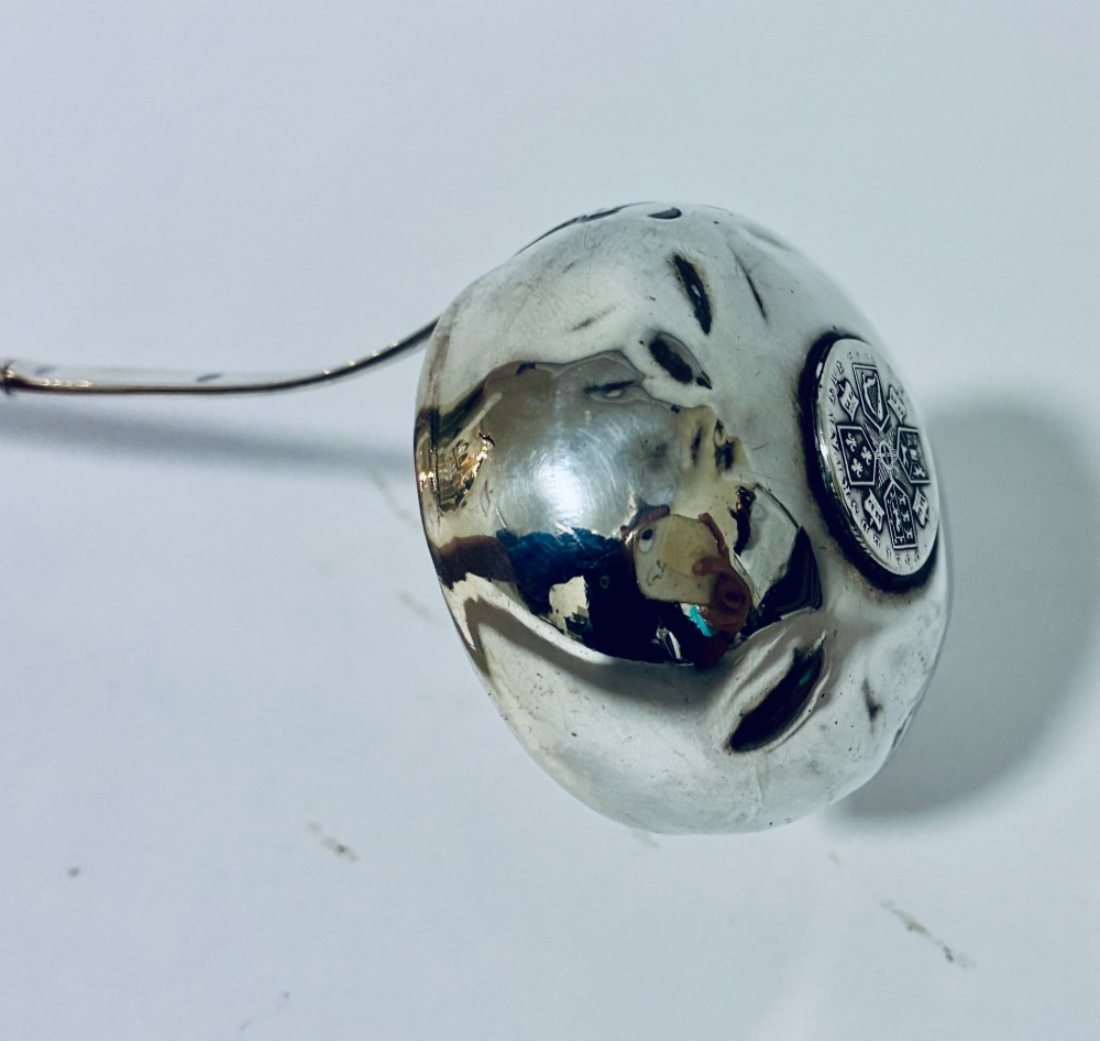 An antique Georgian silver toddy ladle featuring a deep circular silver bowl attached to a long, dark twisted handle. View VII