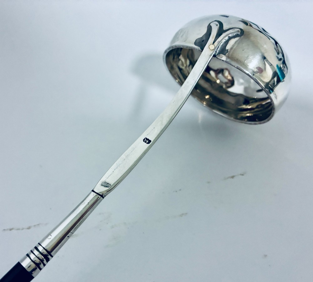 An antique Georgian silver toddy ladle featuring a deep circular silver bowl attached to a long, dark twisted handle. View XII
