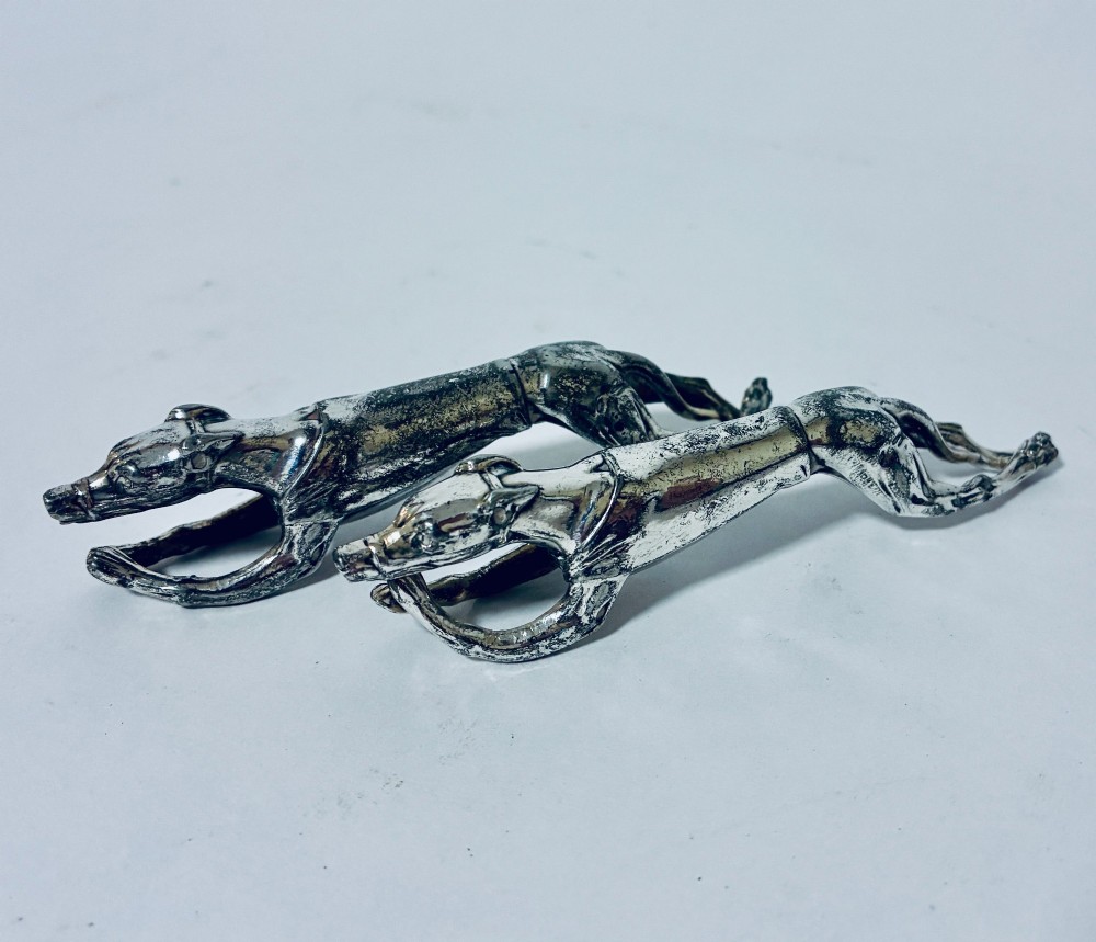 A pair of silver-plated knife rests sculpted in the form of running greyhounds with outstretched legs.