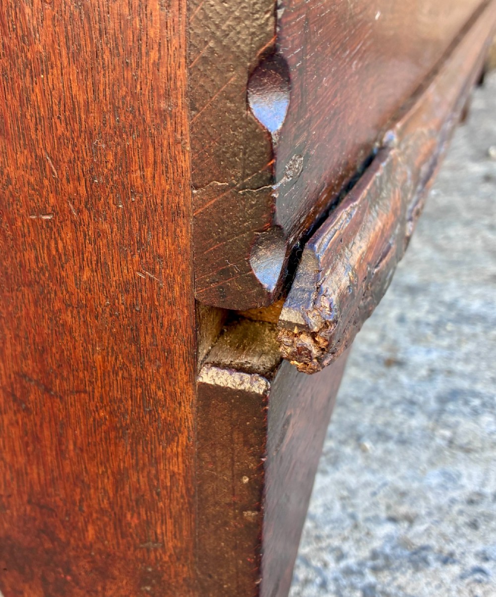 A long early 18th-century oak sword chest featuring a hinged lid, hand-carved initials H R, the date 1724 on the front panel, and a central iron escutcheon. View XV