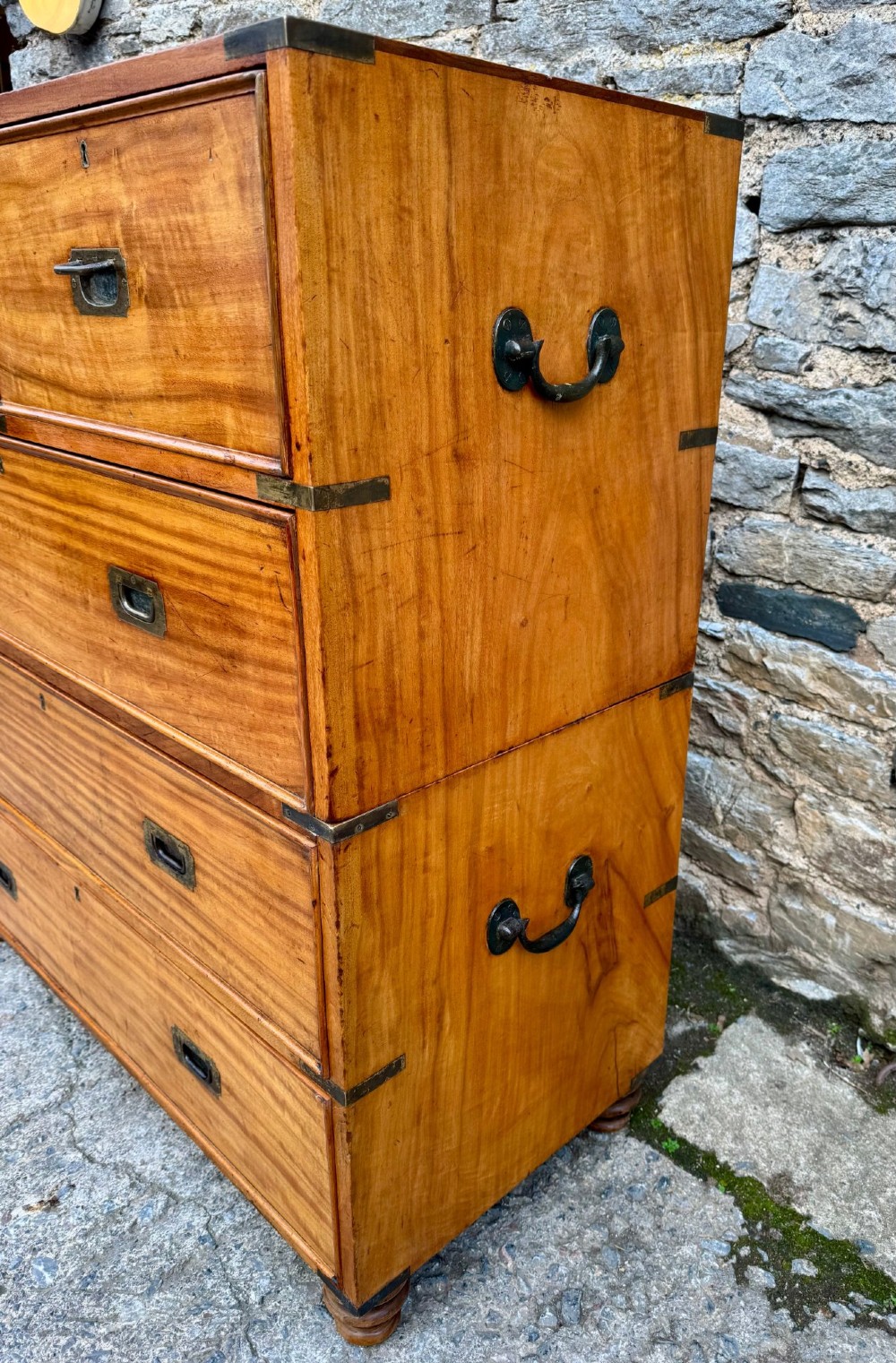 A Victorian camphor wood military campaign chest of drawers featuring two short over three long drawers with flush brass handles, corner straps, and turned feet. View III