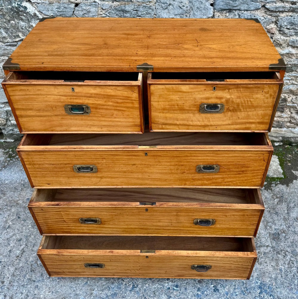 A Victorian camphor wood military campaign chest of drawers featuring two short over three long drawers with flush brass handles, corner straps, and turned feet. View IX