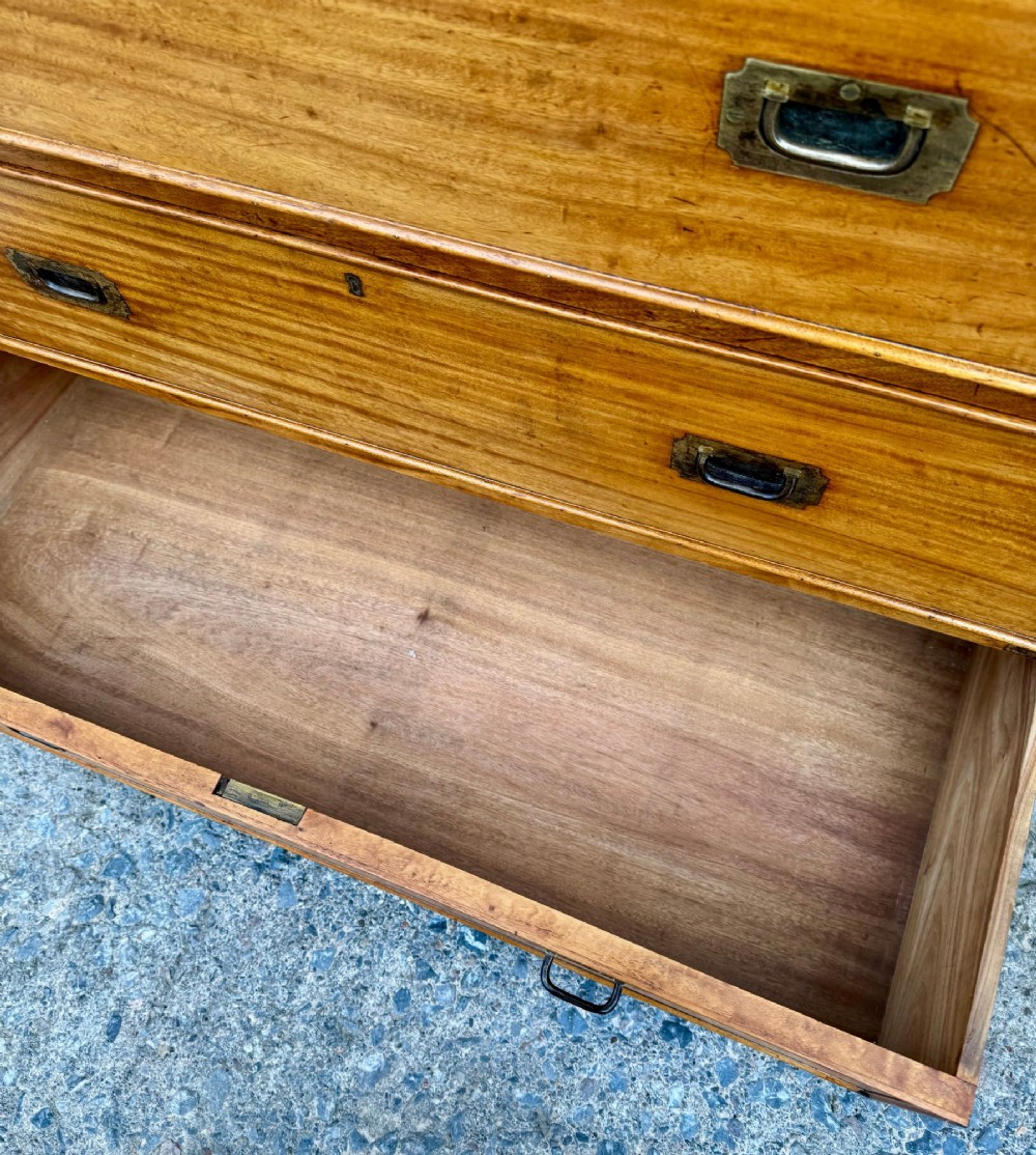 A Victorian camphor wood military campaign chest of drawers featuring two short over three long drawers with flush brass handles, corner straps, and turned feet. View X