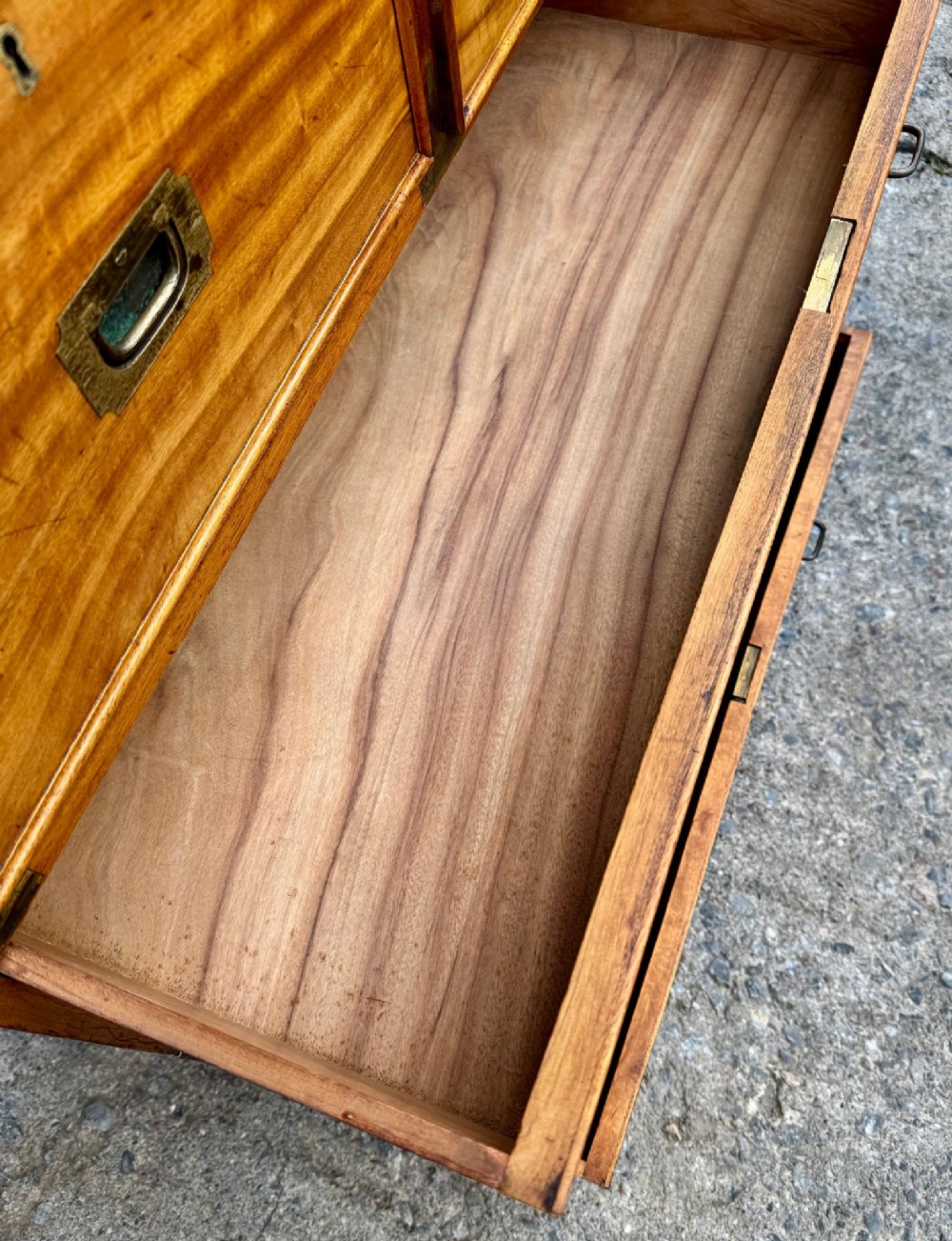 A Victorian camphor wood military campaign chest of drawers featuring two short over three long drawers with flush brass handles, corner straps, and turned feet. View XI