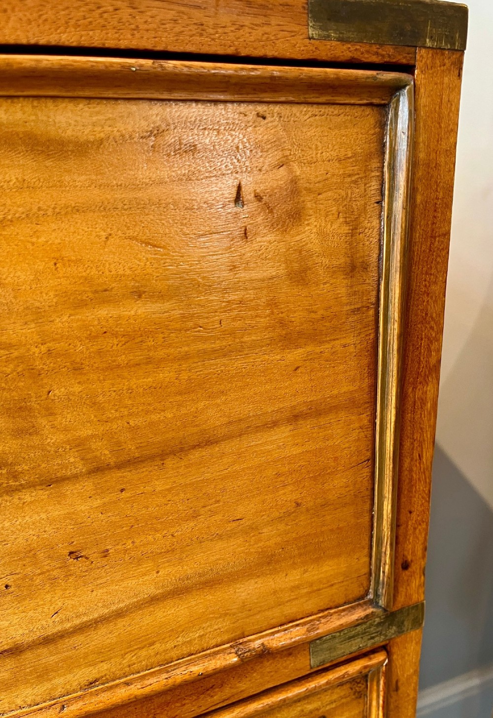 A Victorian camphor wood military campaign chest of drawers featuring two short over three long drawers with flush brass handles, corner straps, and turned feet. View XIV