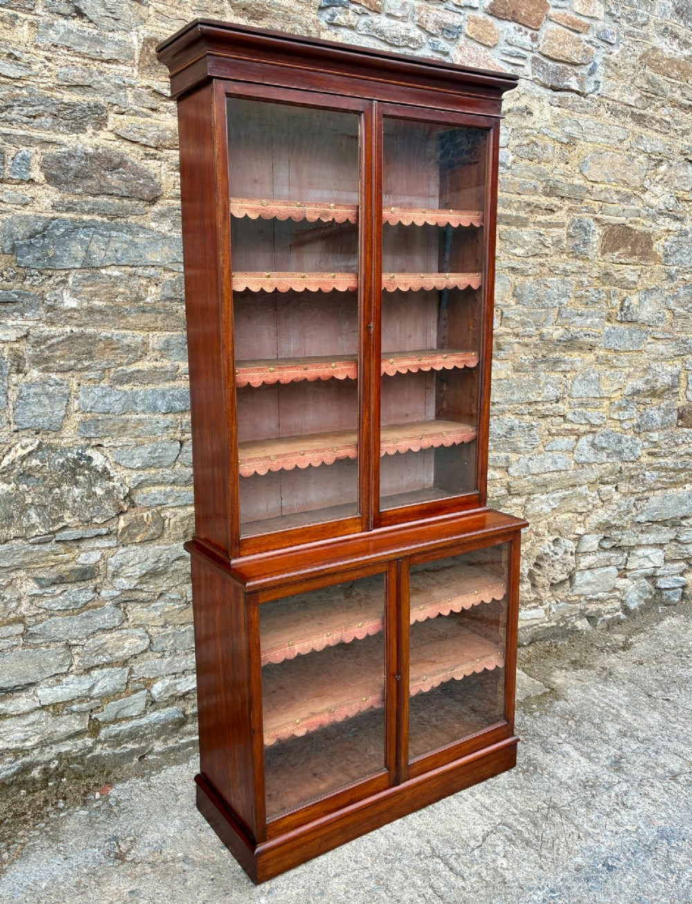 A tall Victorian mahogany cabinet featuring an upper two-door glazed section with scalloped shelf edging set above a lower matching glazed cupboard. View II