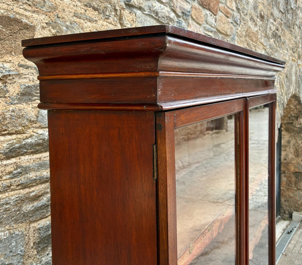 A tall Victorian mahogany cabinet featuring an upper two-door glazed section with scalloped shelf edging set above a lower matching glazed cupboard. View XV